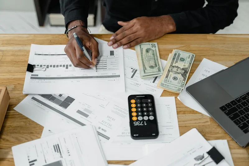 Business owner reviewing financial reports and payment transaction records with a calculator and laptop