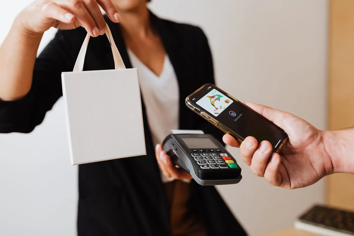 Hand using smartphone for contactless payment at a terminal
